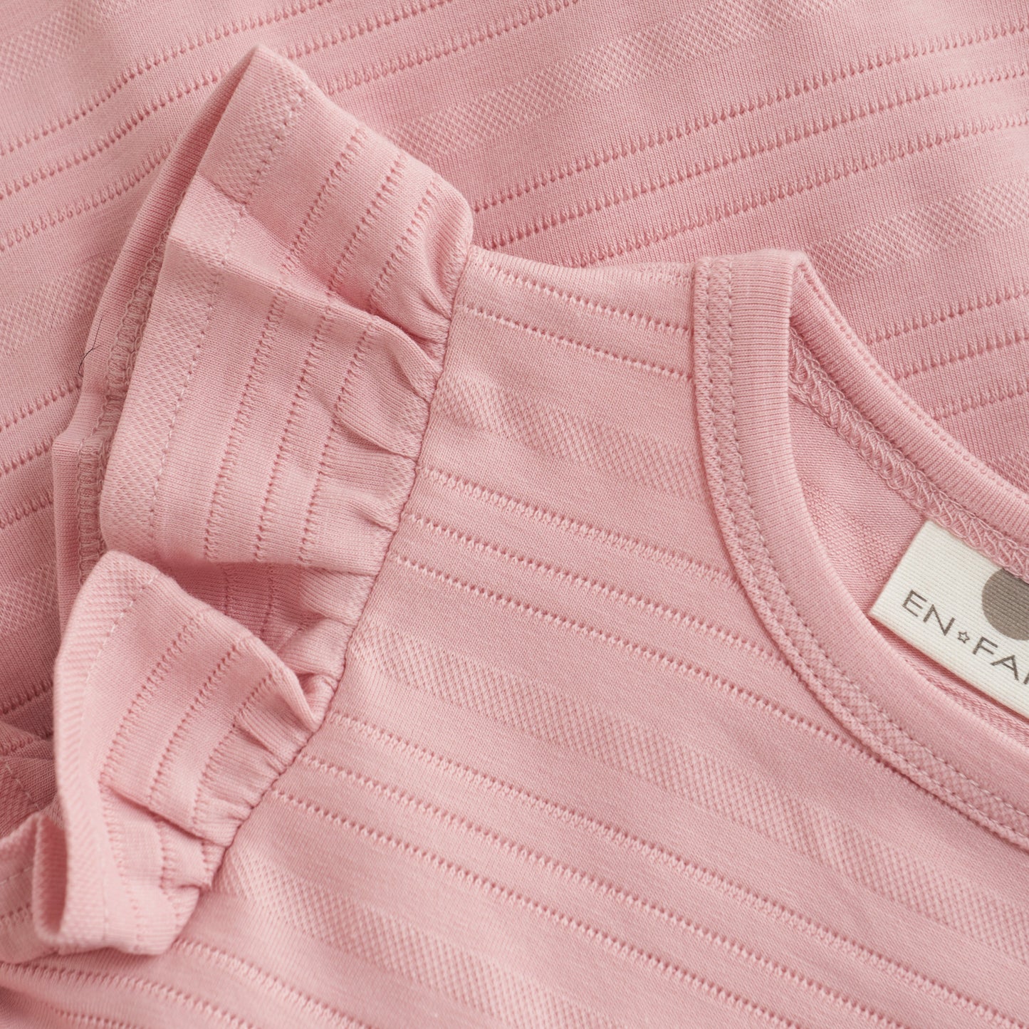Close up product image of a soft pink baby dress
