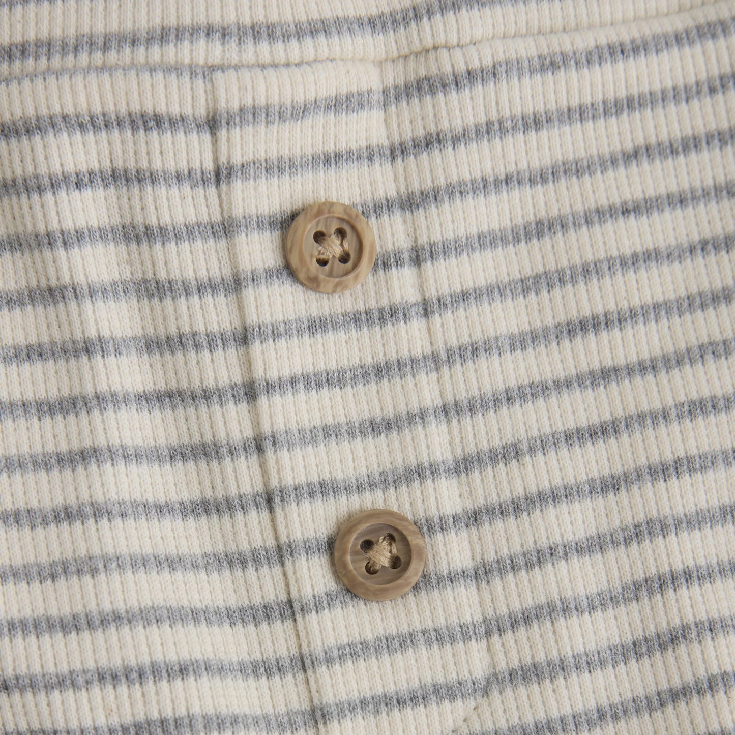 Close up product image of baby leggings with two small wooden buttons in light grey stripes on ivory