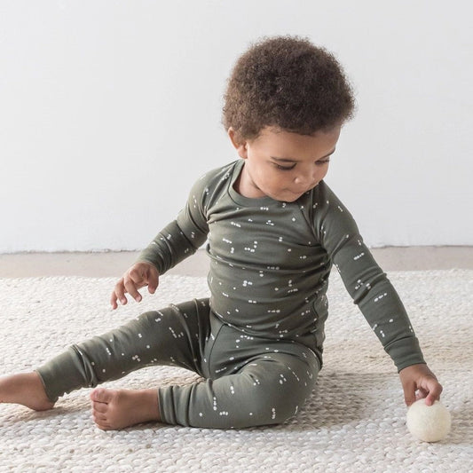 small toddler sitting in a two-piece dark green pyjama set