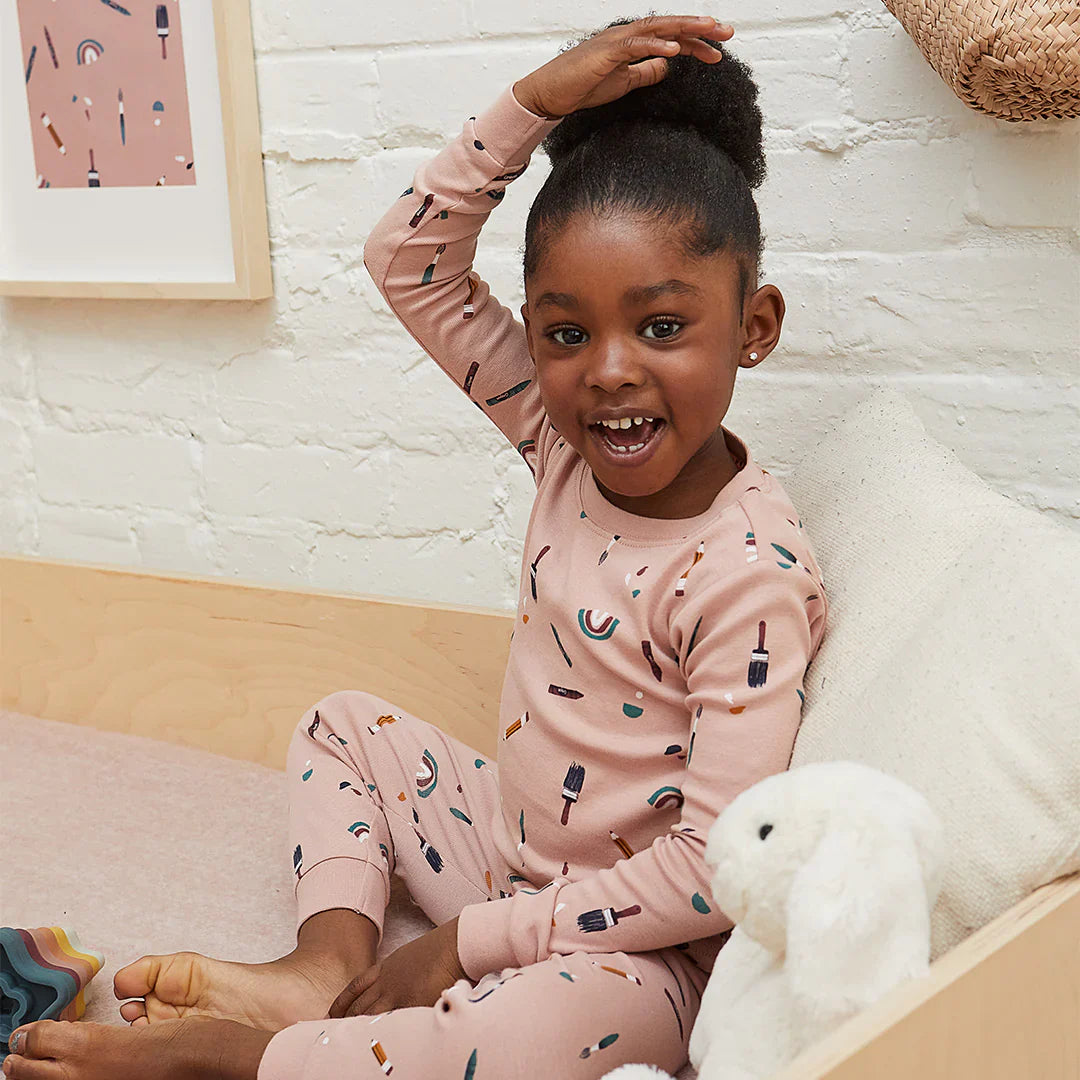young girl sitting in a bed wearing a pair of pink pyjamas