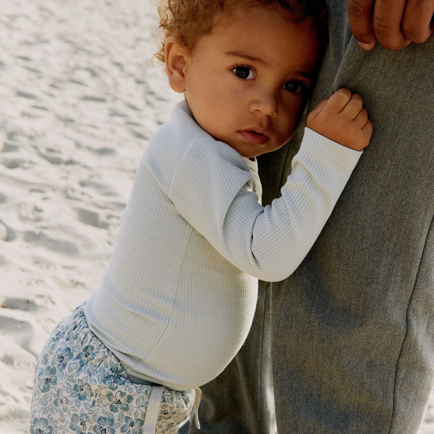 Lifestyle product image of baby in a dress playing on the beach