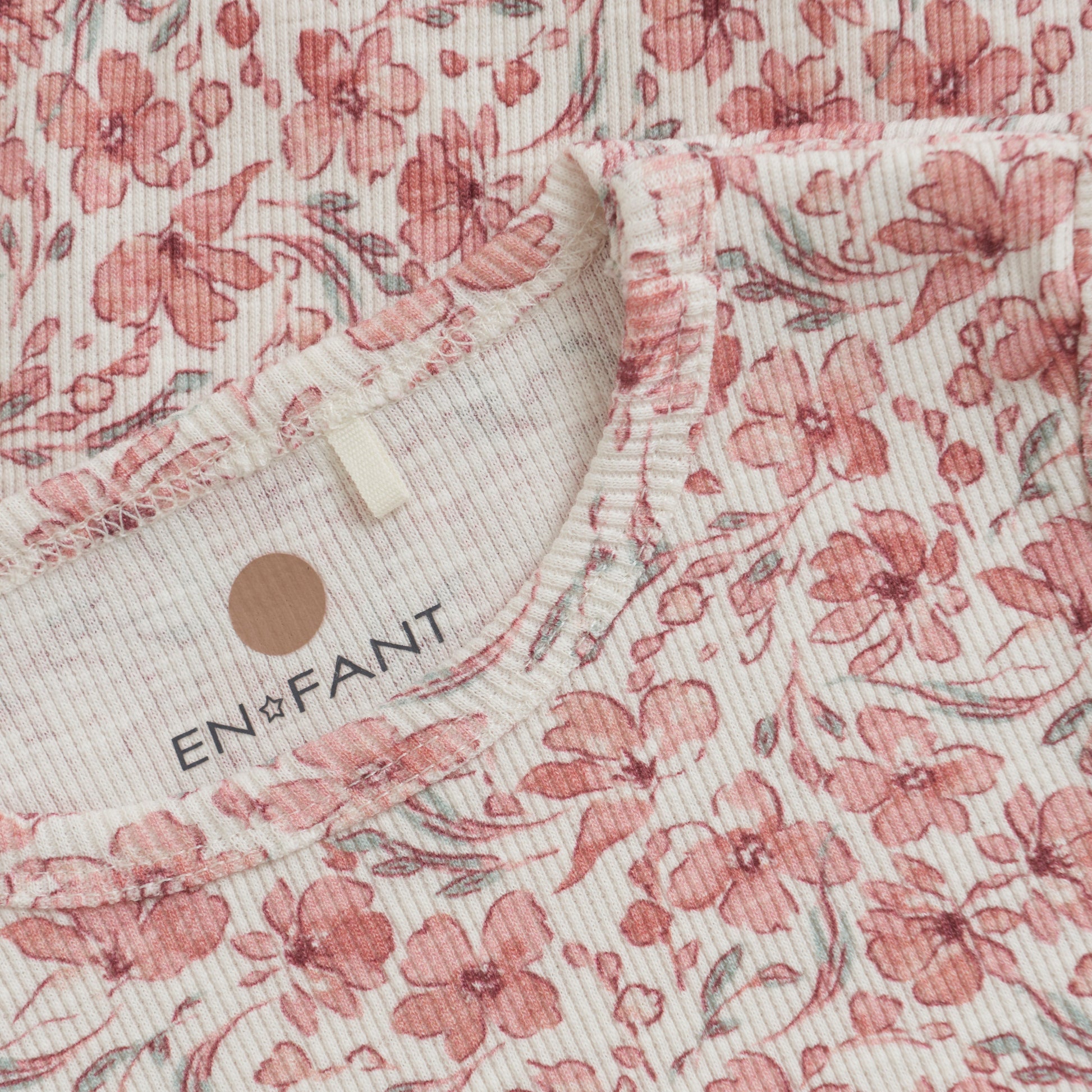 Close up product image of an ivory baby bodysuit with a bright floral print
