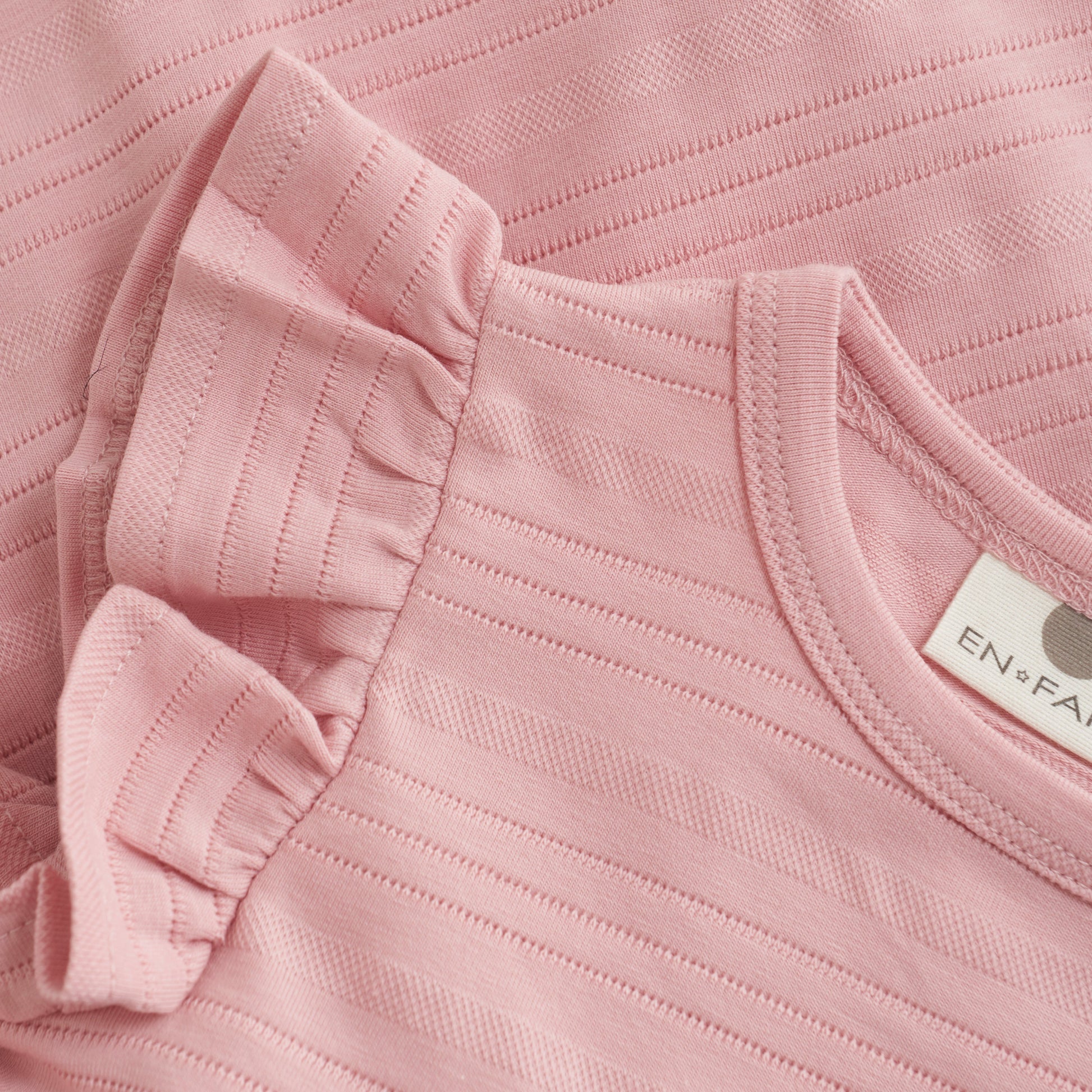 Close up product image of a soft pink baby dress