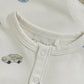 Close up product image of ivory baby playsuit with car print