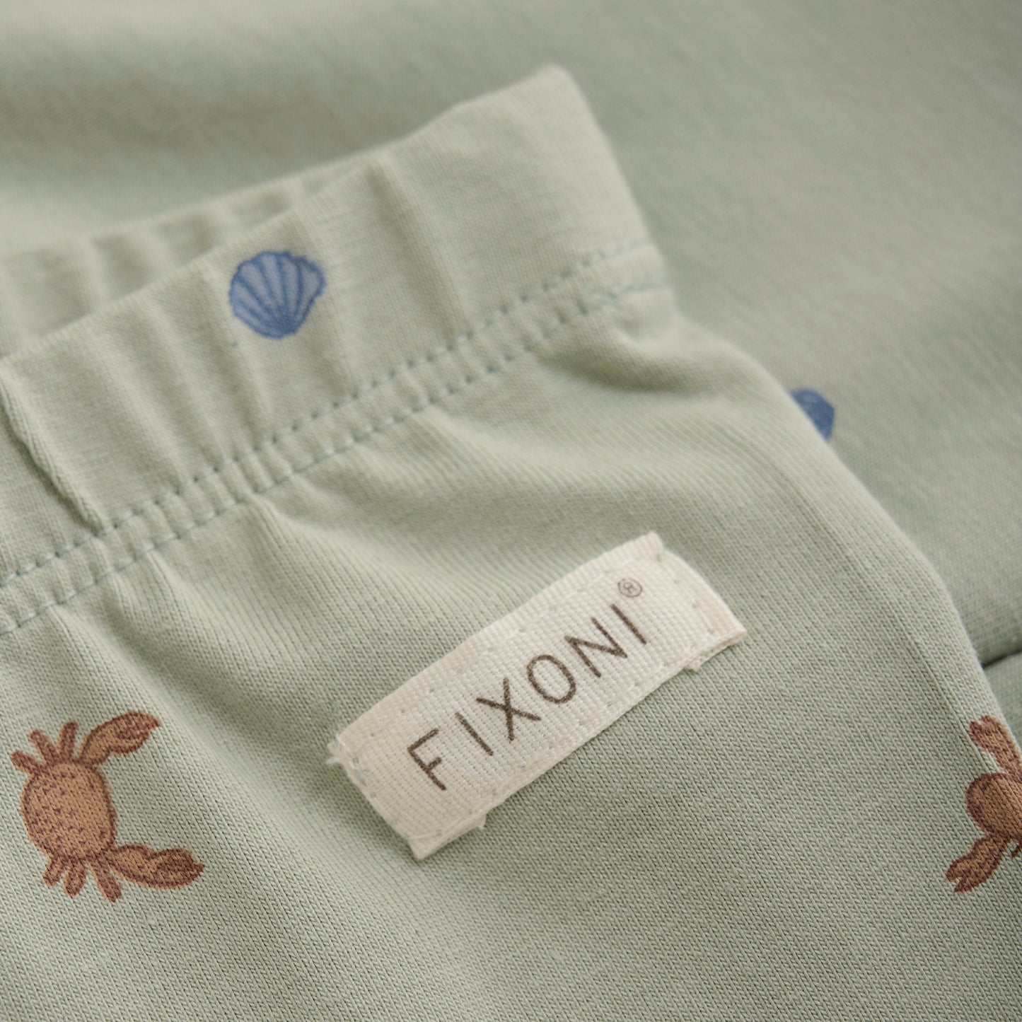 Close up product image of baby leggings in a green desert print