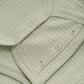 Close up product image of a long sleeve wrap front baby bodysuit in soft green