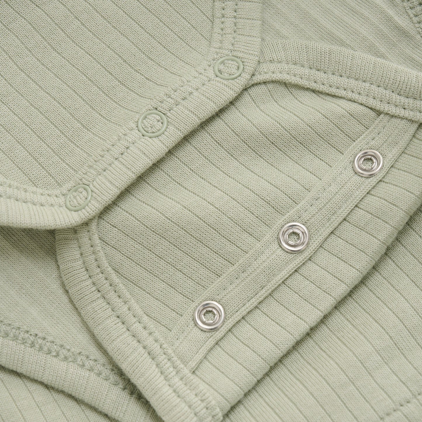 Close up product image of a long sleeve wrap front baby bodysuit in soft green