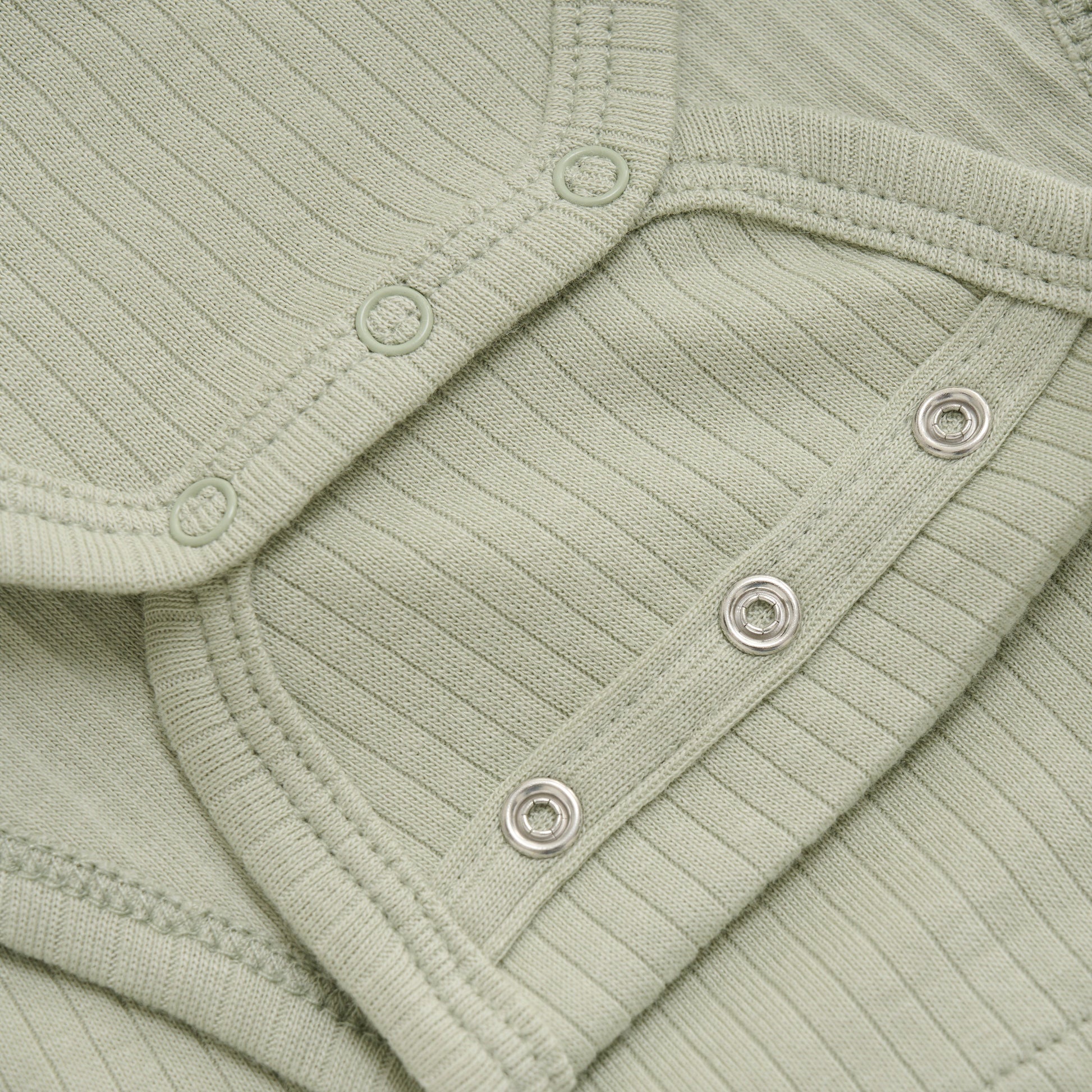 Close up product image of a long sleeve wrap front baby bodysuit in soft green