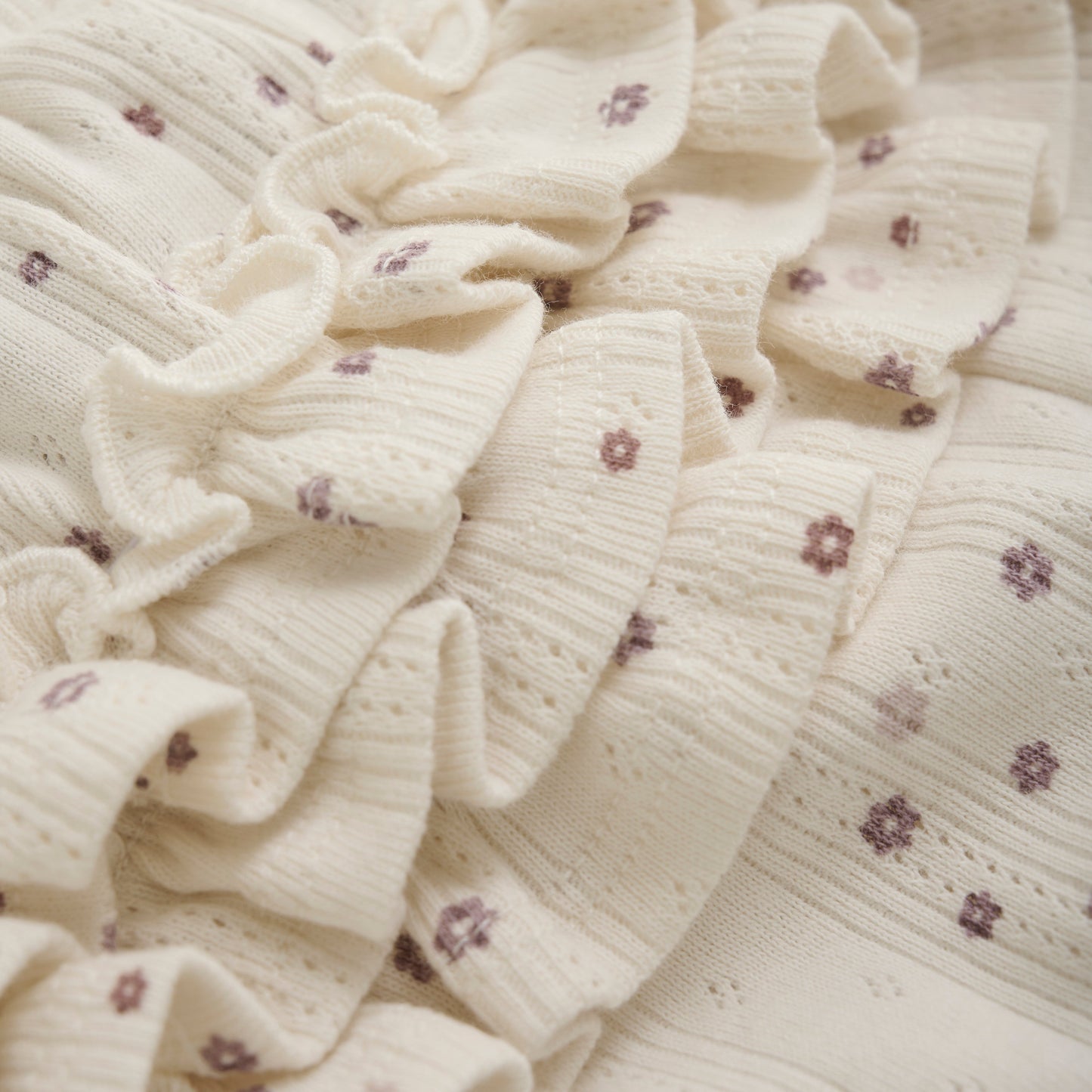 Close up product image of ivory pointelle bloomer baby shorts with a purple daisy print