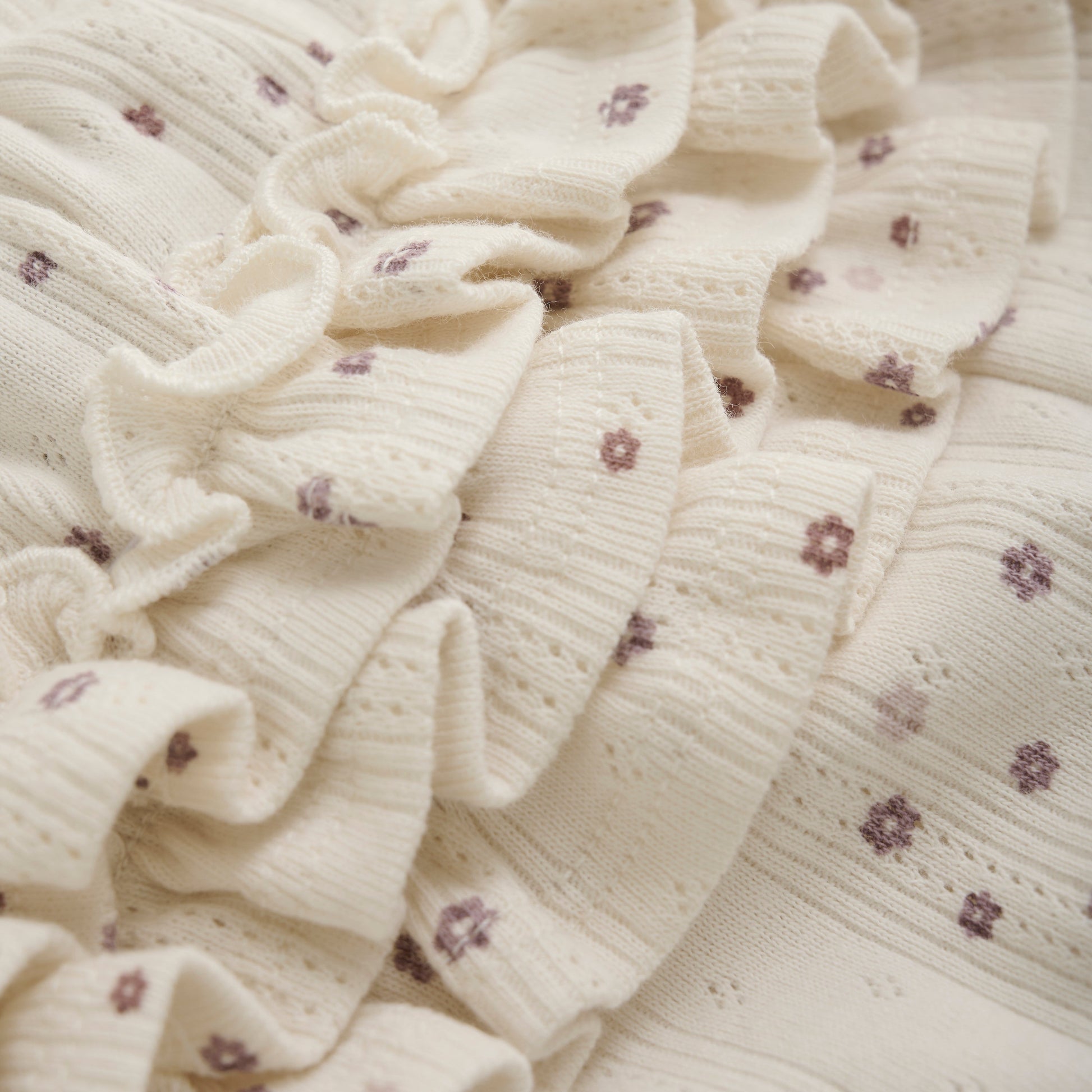 Close up product image of ivory pointelle bloomer baby shorts with a purple daisy print