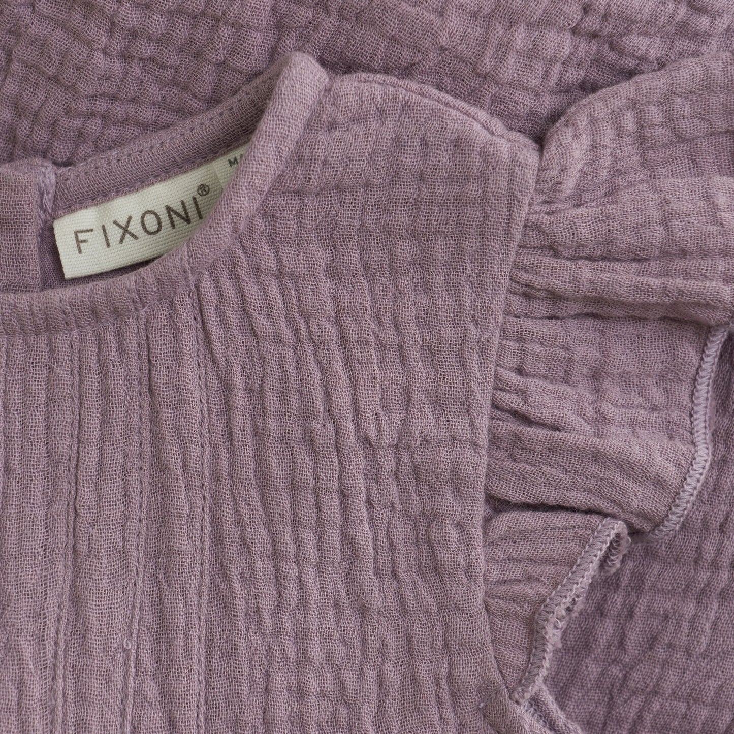 Close up product image of a woven ruffle sleeve baby bodysuit in purple