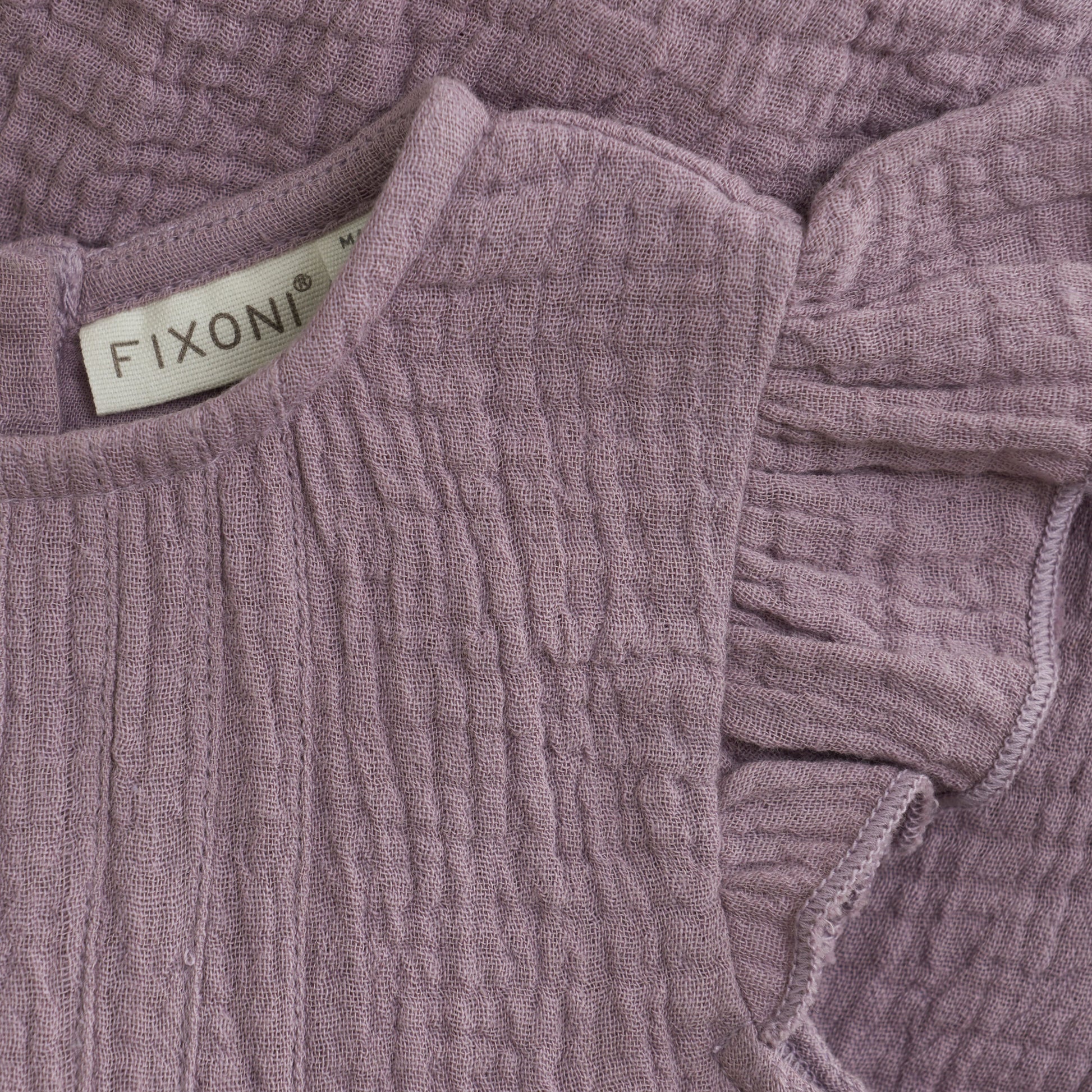 Close up product image of a woven ruffle sleeve baby bodysuit in purple