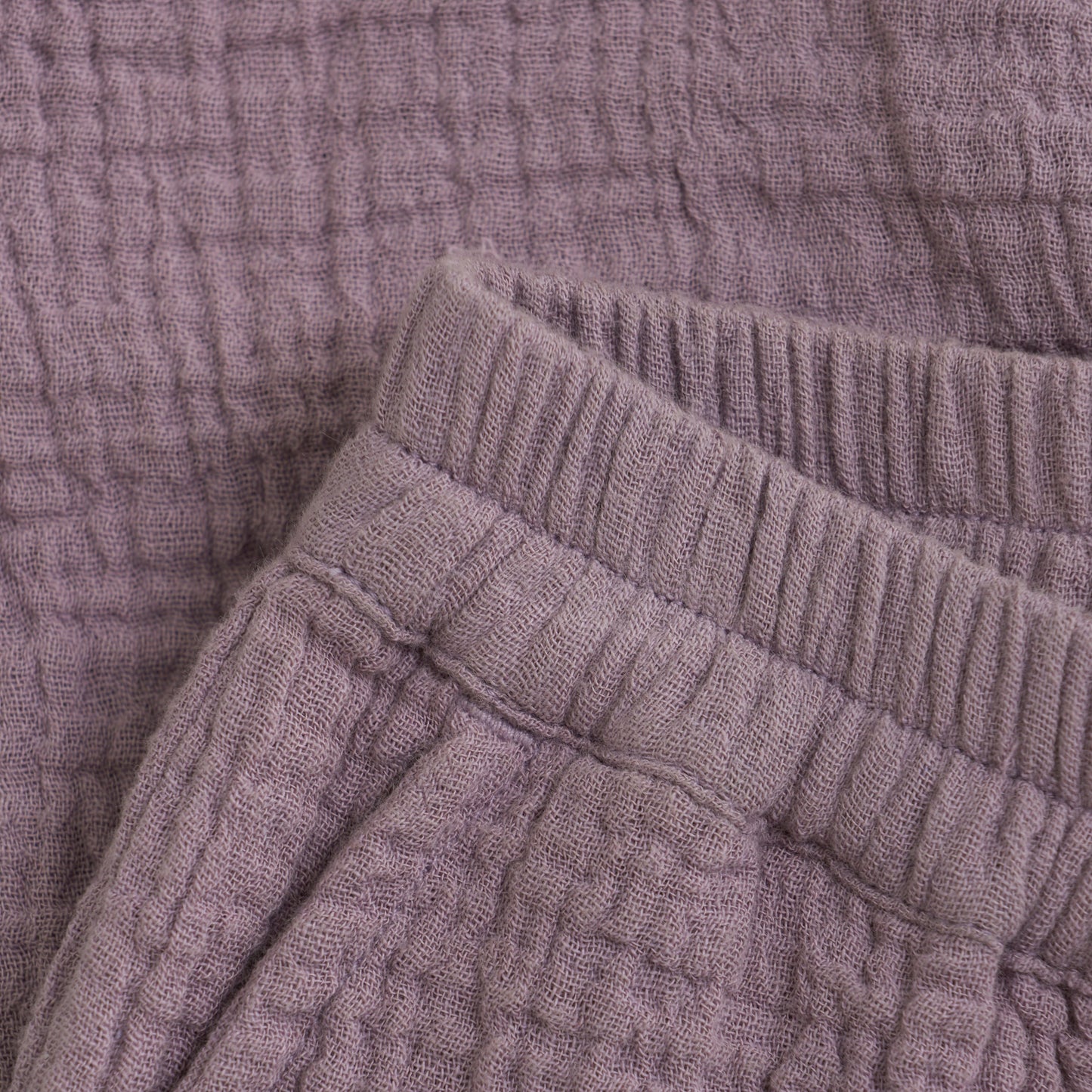 Close up product image of woven baby trousers in purple