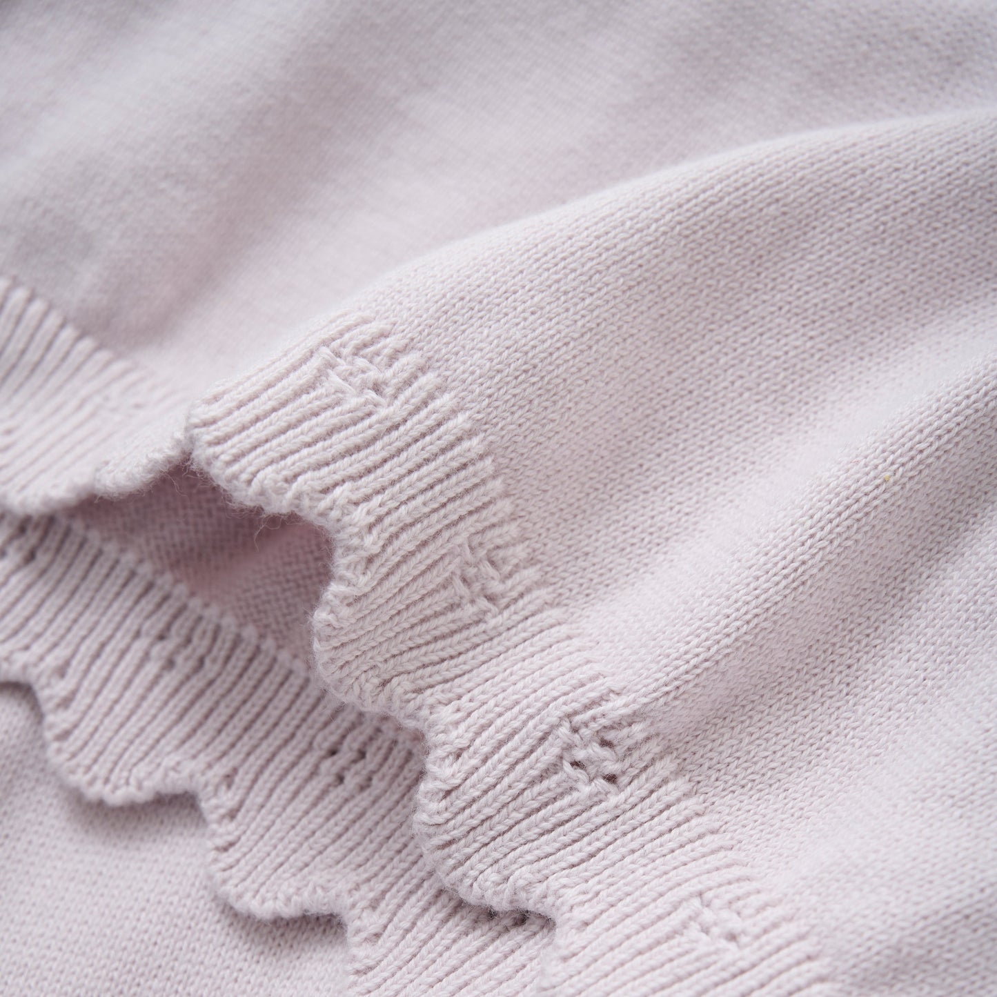Close up product image of a knit baby dress in light lilac