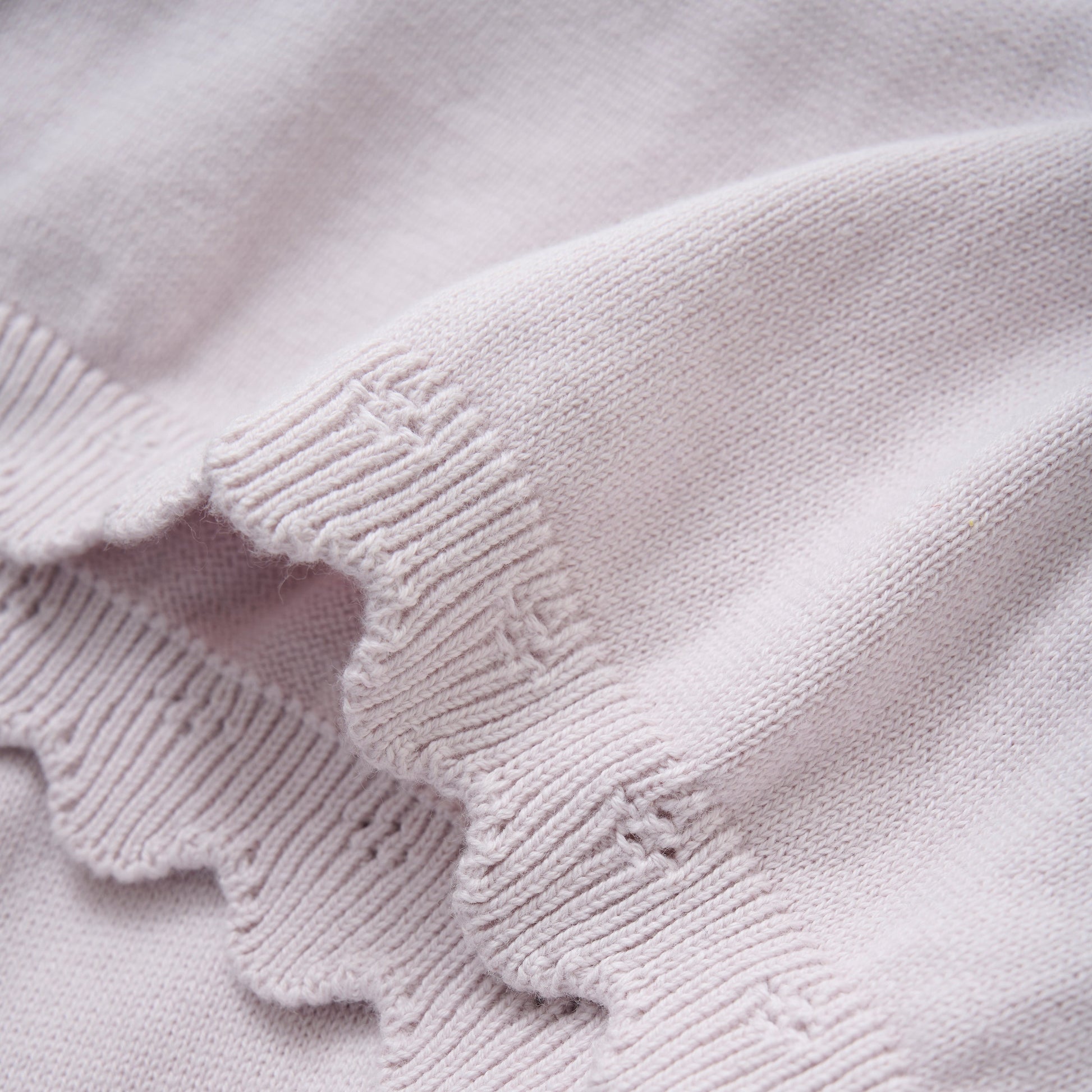 Close up product image of a knit baby dress in light lilac