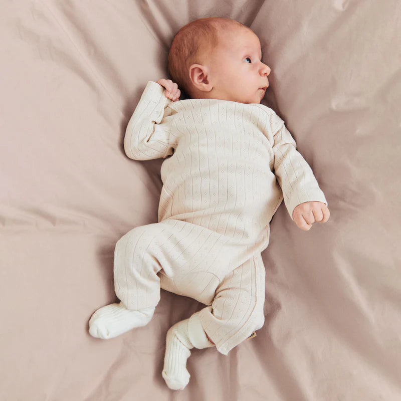 Lifestyle product image of a child holding a rainbow sweater across her back