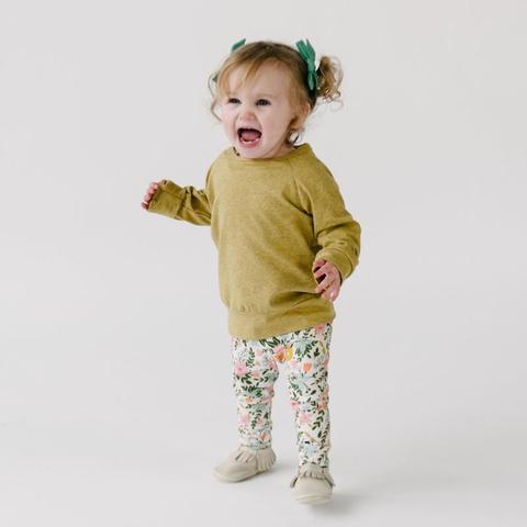 toddler standing in a pair of floral leggings and a sweatshirt