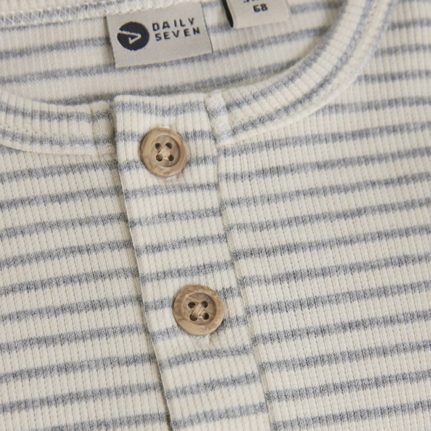 Close up product image of a long sleeved baby bodysuit with light grey stripes on ivory