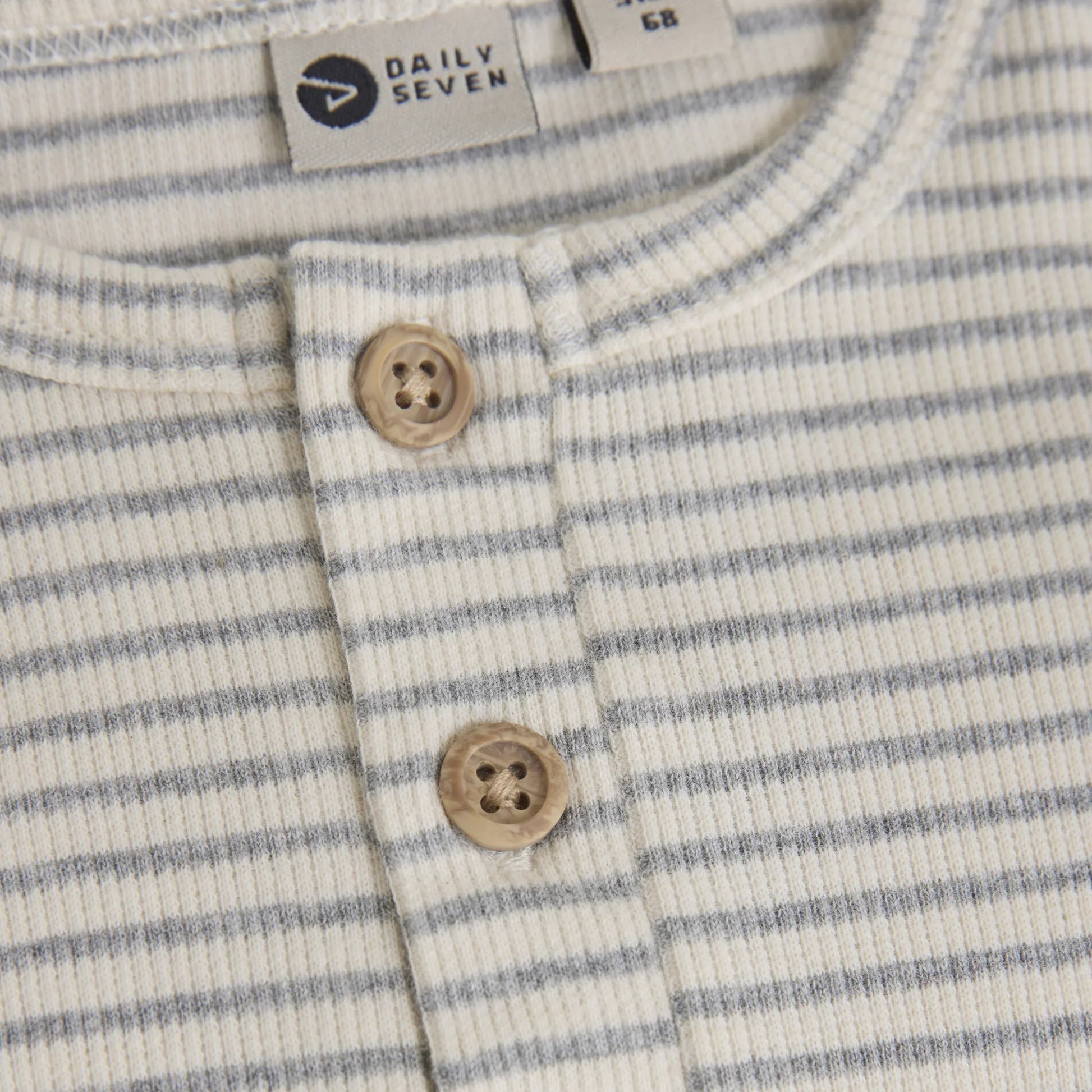 Close up product image of a long sleeved baby bodysuit with light grey stripes on ivory