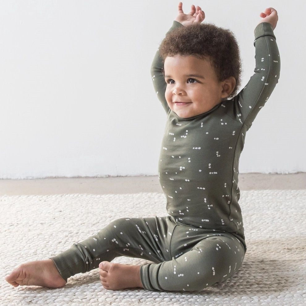 small toddler sitting in a two-piece dark green pyjama set