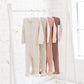 Four baby sleepers hanging on a clothing rail in earthy pink shades and beige neutrals