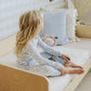 young girl sitting in a bed wearing a pair of pink pyjamas