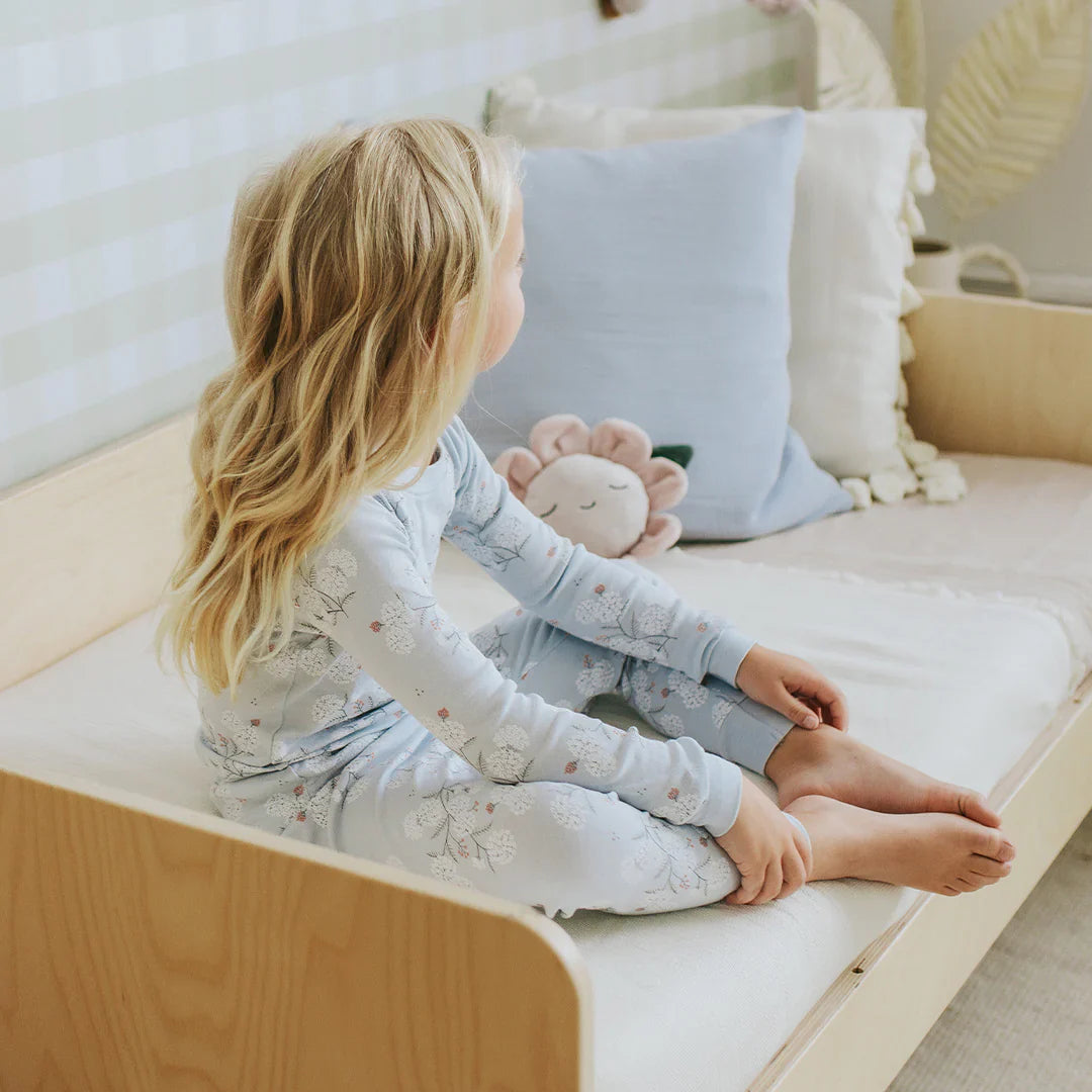 young girl sitting in a bed wearing a pair of pink pyjamas