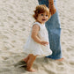 Lifestyle product image of baby in a dress playing on the beach
