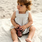 Lifestyle product image of baby in a dress playing on the beach